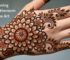 A beautiful, intricate chrysanthemum mehndi design on the back of a hand, showcasing modern floral henna art.